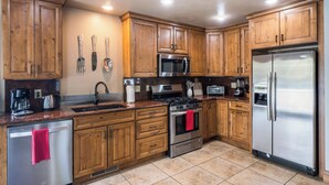A kitchen with wooden cabinets, stainless steel appliances, and a tiled floor. - Newly Updated Mtn House! Walk to Golf/Tennis/Park, Hot Tub, Firepit, Ping Pong (Angel Fire)