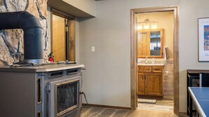 A kitchen with a stone wall, a stove, and a wooden cabinet. - Newly Updated Mtn House! Walk to Golf/Tennis/Park, Hot Tub, Firepit, Ping Pong (Angel Fire)