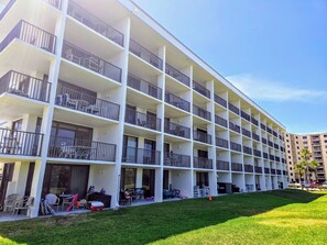 Un hôtel à plusieurs étages doté de balcons, d’un espace extérieur aménagé pour s’asseoir et d’une pelouse bien entretenue.