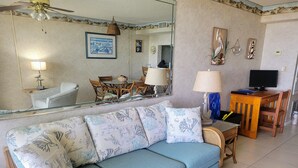 A living room with a blue sofa, wooden furniture, a dining table, and a television.