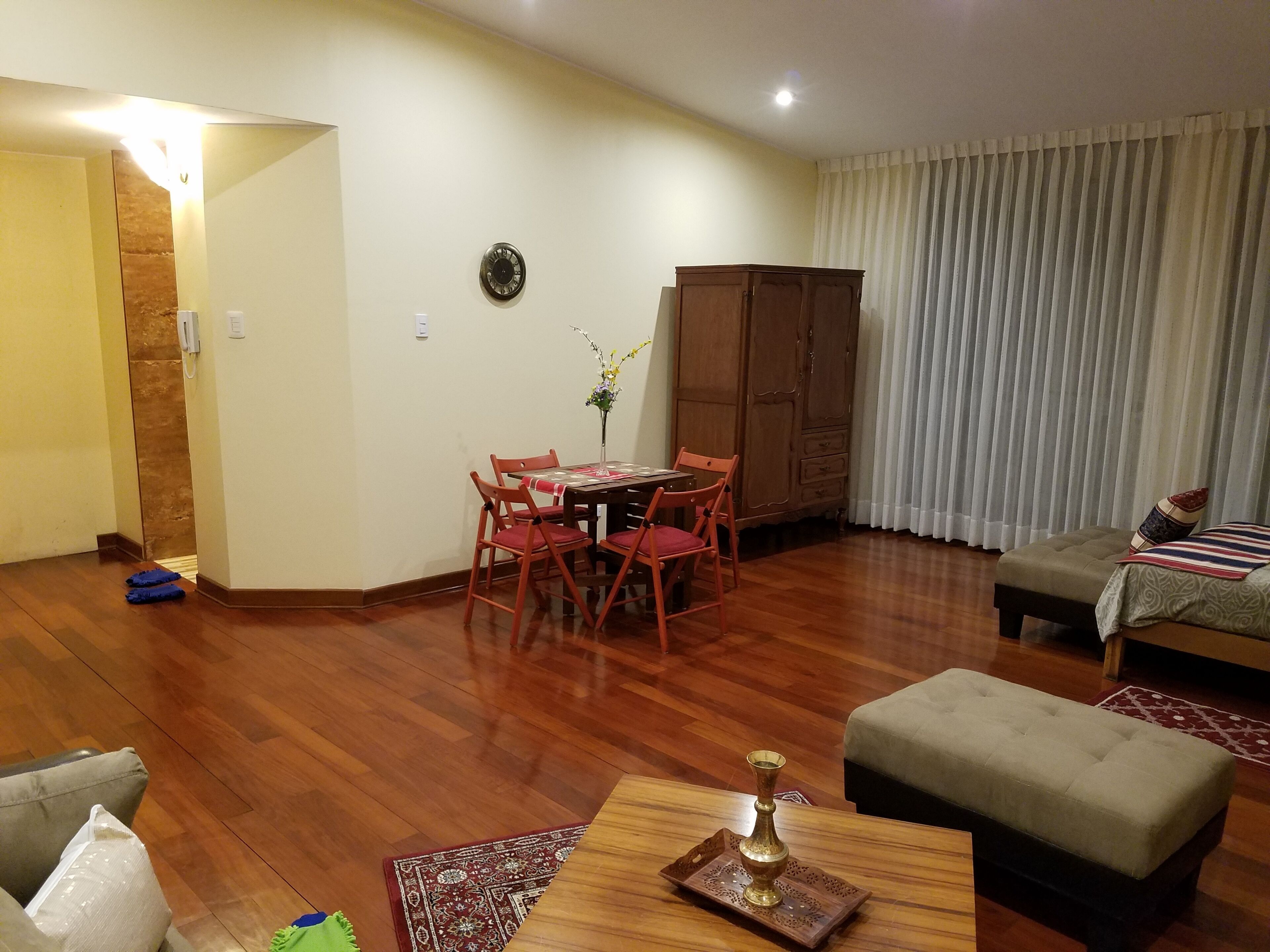 A living room with a dining table, chairs, a sofa, and a cabinet.