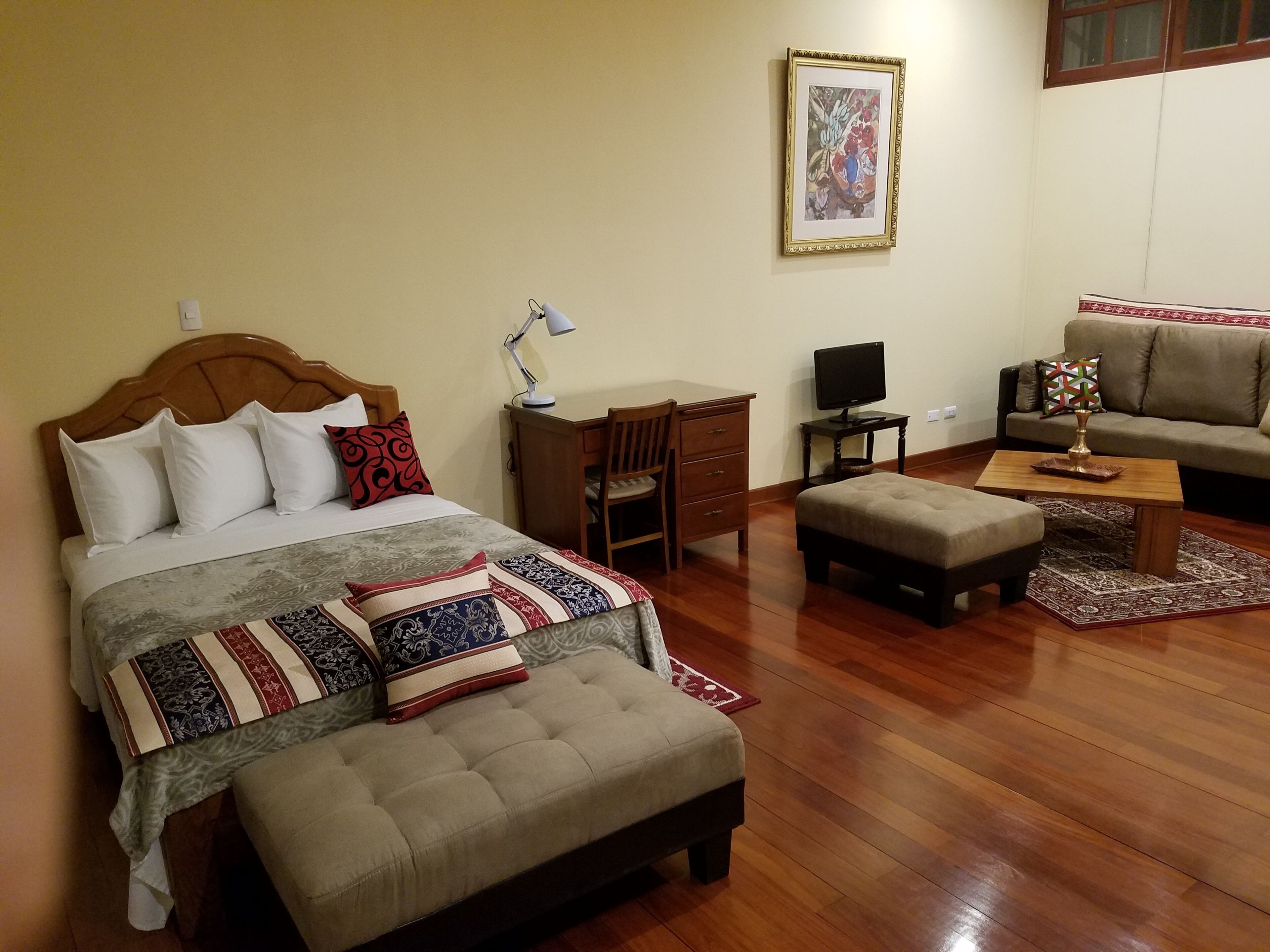 Una habitació ben equipada amb llit, escriptori, cadira, sofà i televisió.