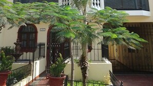 Un edificio residencial de varios pisos con balcones, ventanas amplias y un patio central con plantas en macetas.