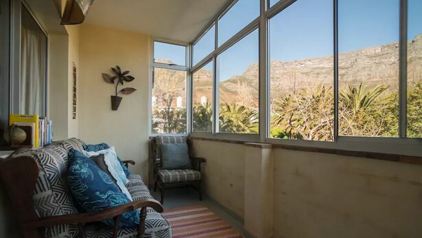 A room with a large window, a sofa, a chair, and a small table.