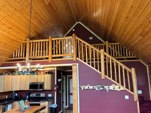 Un intérieur en bois comprenant une cuisine, un coin repas et un escalier menant à un niveau supérieur.