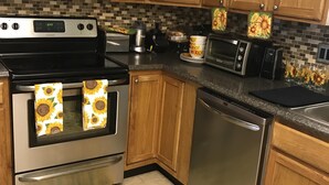 A kitchen with wooden cabinets, stainless steel appliances, and sunflower-themed kitchen towels.