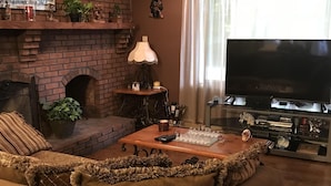 A cozy living room with a brick fireplace, a large flat-screen TV, and a comfortable sofa.
