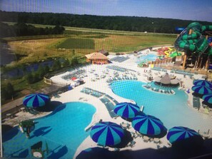 Ein Wasserpark mit mehreren Pools, Sonnenschirmen und einer großen Rutsche.