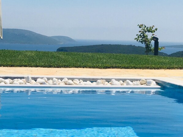Una piscina con vistas al mar y a las colinas.