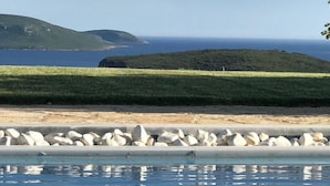 Una piscina con vista al océano y un área con césped.