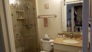 A bathroom with a glass-enclosed shower, a toilet, a sink with a mirror, and a towel rack.