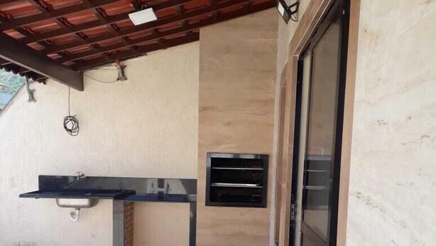 Un patio couvert comprenant un évier intégré, un petit système de ventilation et une porte-fenêtre coulissante.