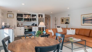 Una sala moderna con una mesa de comedor de madera, sillas negras y un sofá marrón.