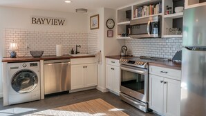 Una cocina moderna con armarios blancos, lavadora integrada, refrigerador de acero inoxidable y microondas.