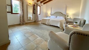 Une chambre à coucher avec un grand lit, une chaise, une petite table et un miroir.