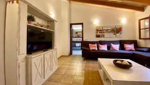 Un salon avec un meuble de rangement blanc pour l’équipement audiovisuel, un ensemble de canapés marron foncé et une table basse blanche.