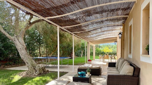 Une terrasse extérieure avec des meubles en osier et une pergola.