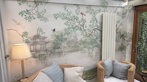 A room with a traditional mural, wicker furniture, and a lamp.