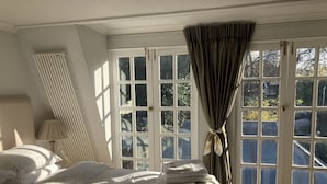 A bedroom with a large bed, a radiator, and a window with curtains.