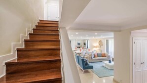A staircase leading to a living area with a sofa, coffee table, and a dining area in the background.