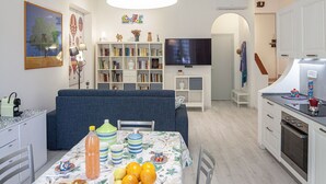 A modern kitchen with a dining area, a TV, and a bookshelf. - Casa Mary - For 4 people, in centre, 5 minutes from beach and station to Cinque Terre (Levanto)