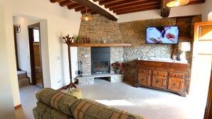 A living room with a stone fireplace, wooden beams, a television, and a sofa. - Wonderful private villa with private pool, internet, A/C, TV, terrace, pets allowed, close to Lucca (Palmata)