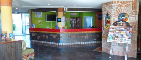 Un área de recepción con piso de baldosas, mostrador de cubierta roja y pared con diseño de mosaico.