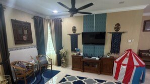 Un salon équipé d’un téléviseur à écran plat, d’un ventilateur de plafond, d’une armoire en bois et d’une tente de jeu à rayures rouges et blanches.
