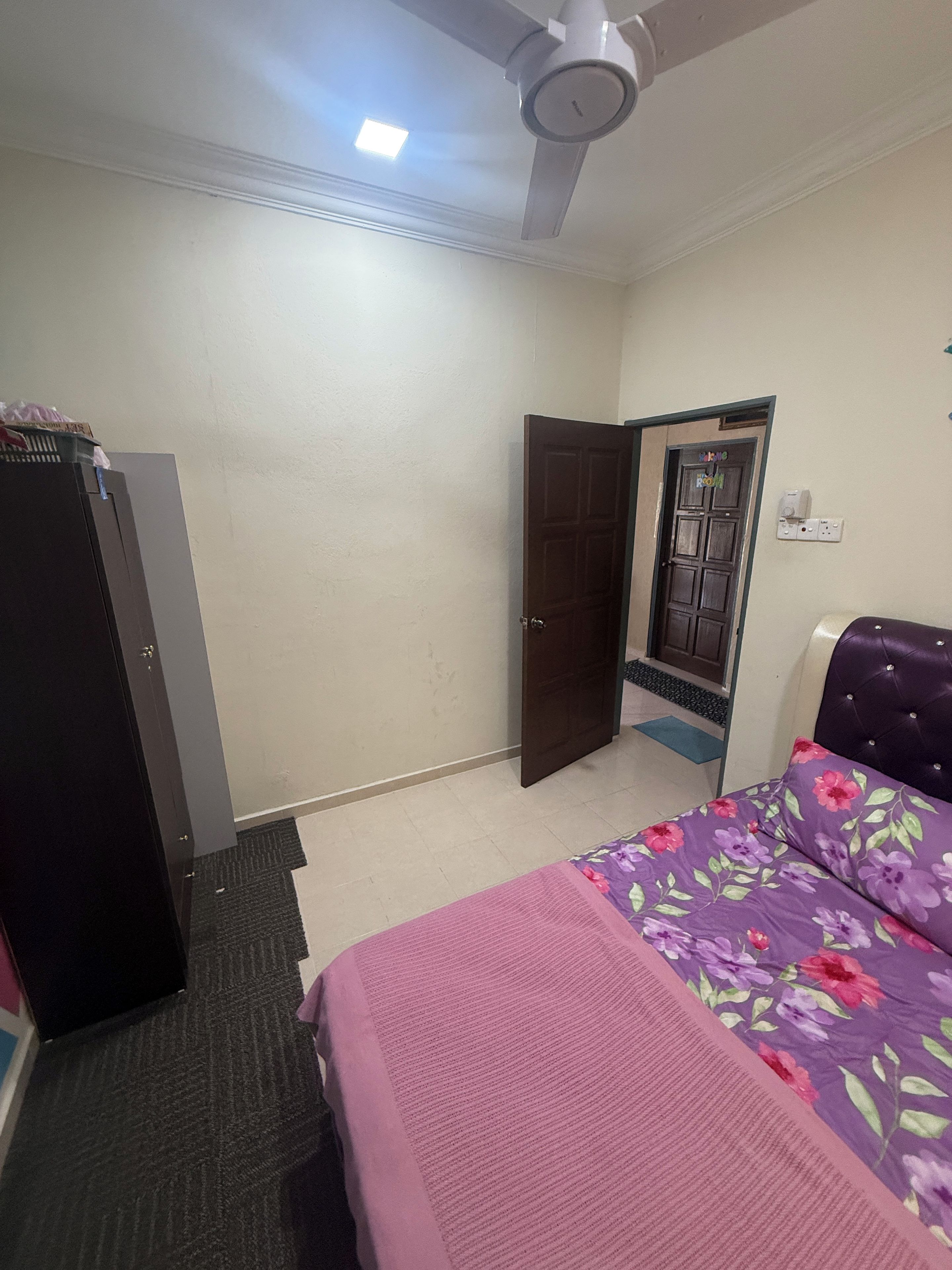 A bedroom with a bed, a wardrobe, a door, and a ceiling fan.