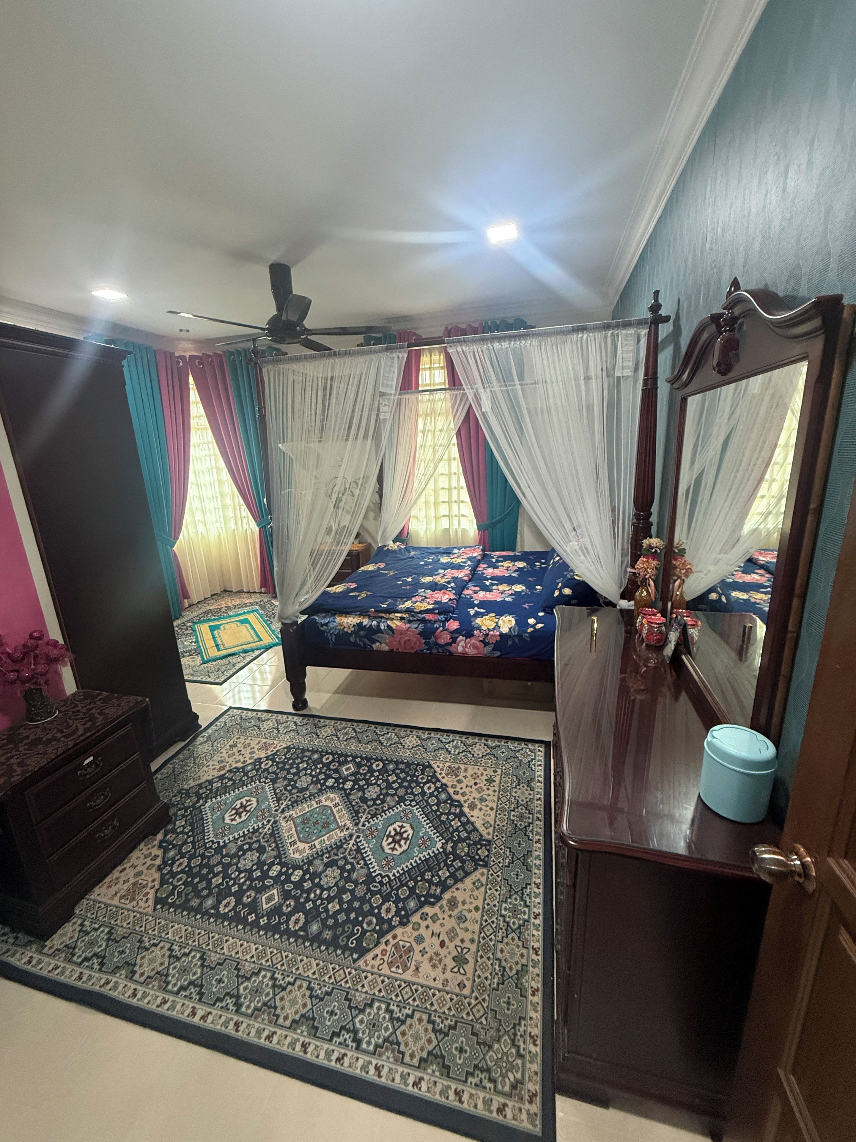 Une chambre à coucher avec un lit, un miroir, une commode, un tapis et un ventilateur de plafond.