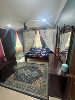 Un dormitorio con cama, espejo, cómoda, alfombra y ventilador de techo.