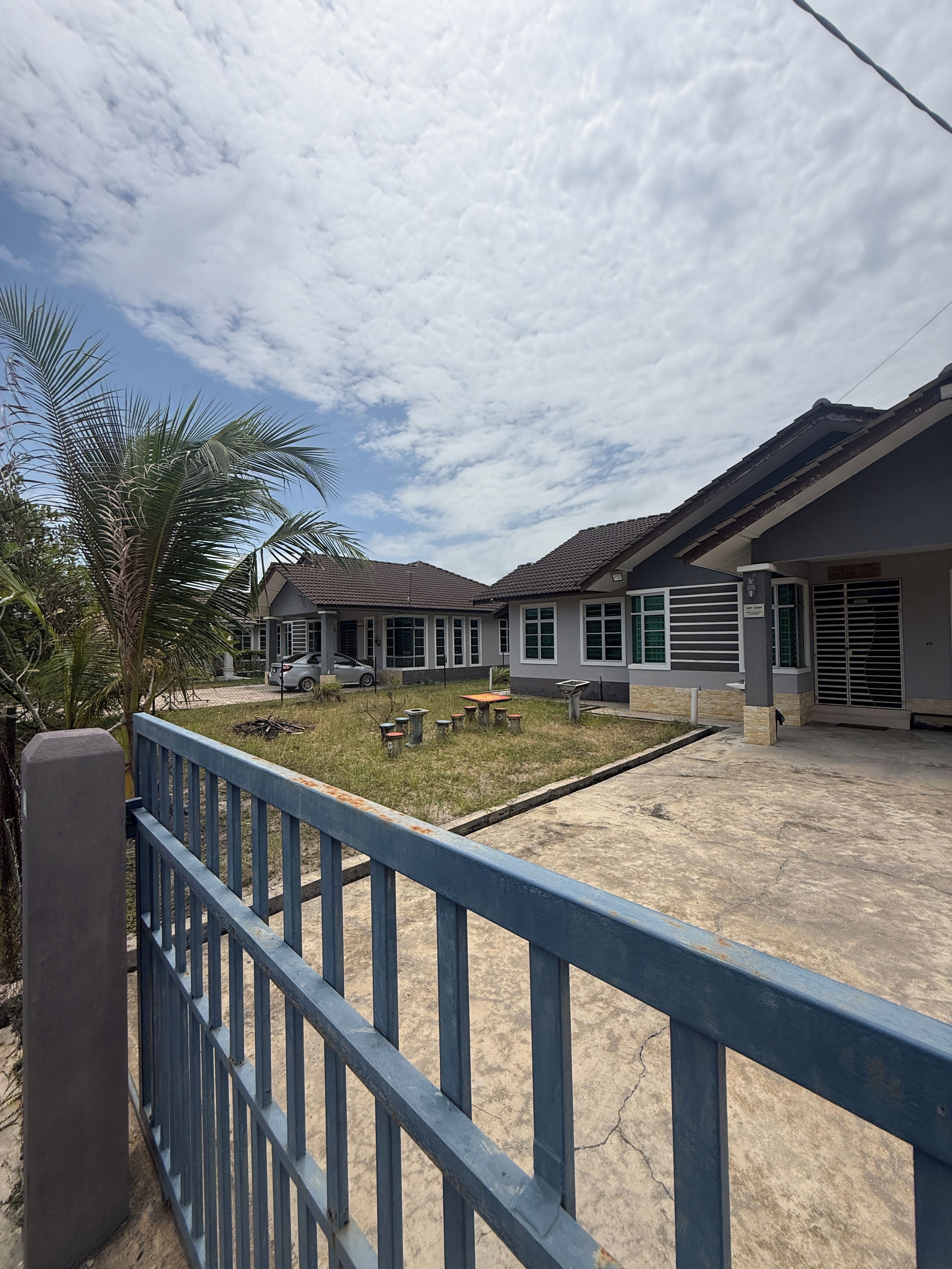 A residential area with a gated entrance, a paved courtyard, and a building with a tiled roof.