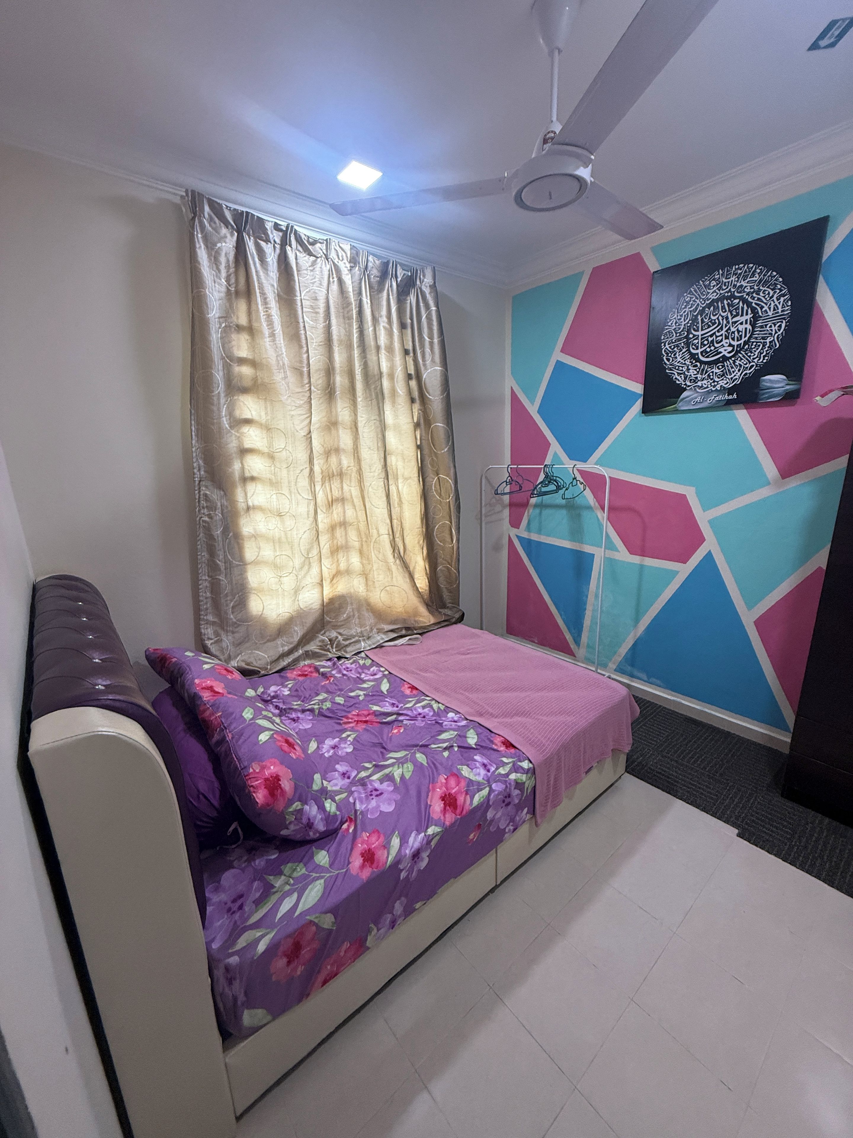 A bedroom with a bed, curtains, a ceiling fan, and a wall-mounted TV.