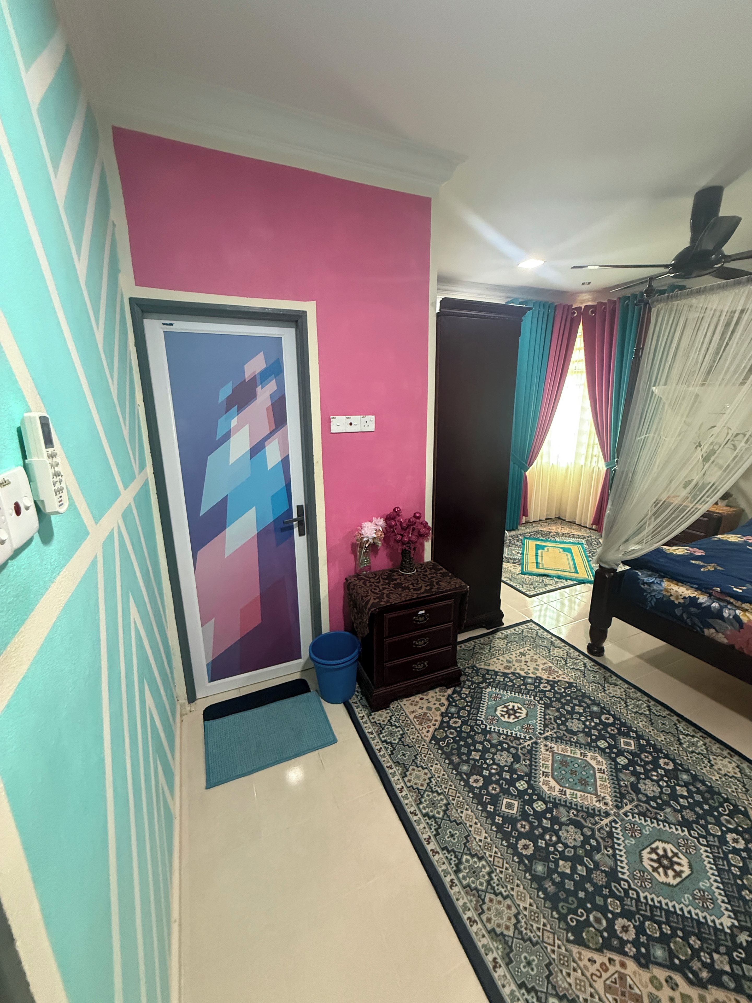 A bedroom with a bed, a nightstand, a decorative rug, a door with a geometric design, and a ceiling fan.