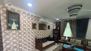 A living room with a patterned wall, a chandelier, a sofa, a wooden cabinet, and a rug.