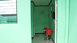 A narrow hallway with green walls, a red chair, and a clock on the wall. - Bulalo Mangrove Inn (Calapan)