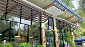 A modern building with a covered entrance, large glass windows, and a stone facade. - Eduardo's Resort (Calapan)