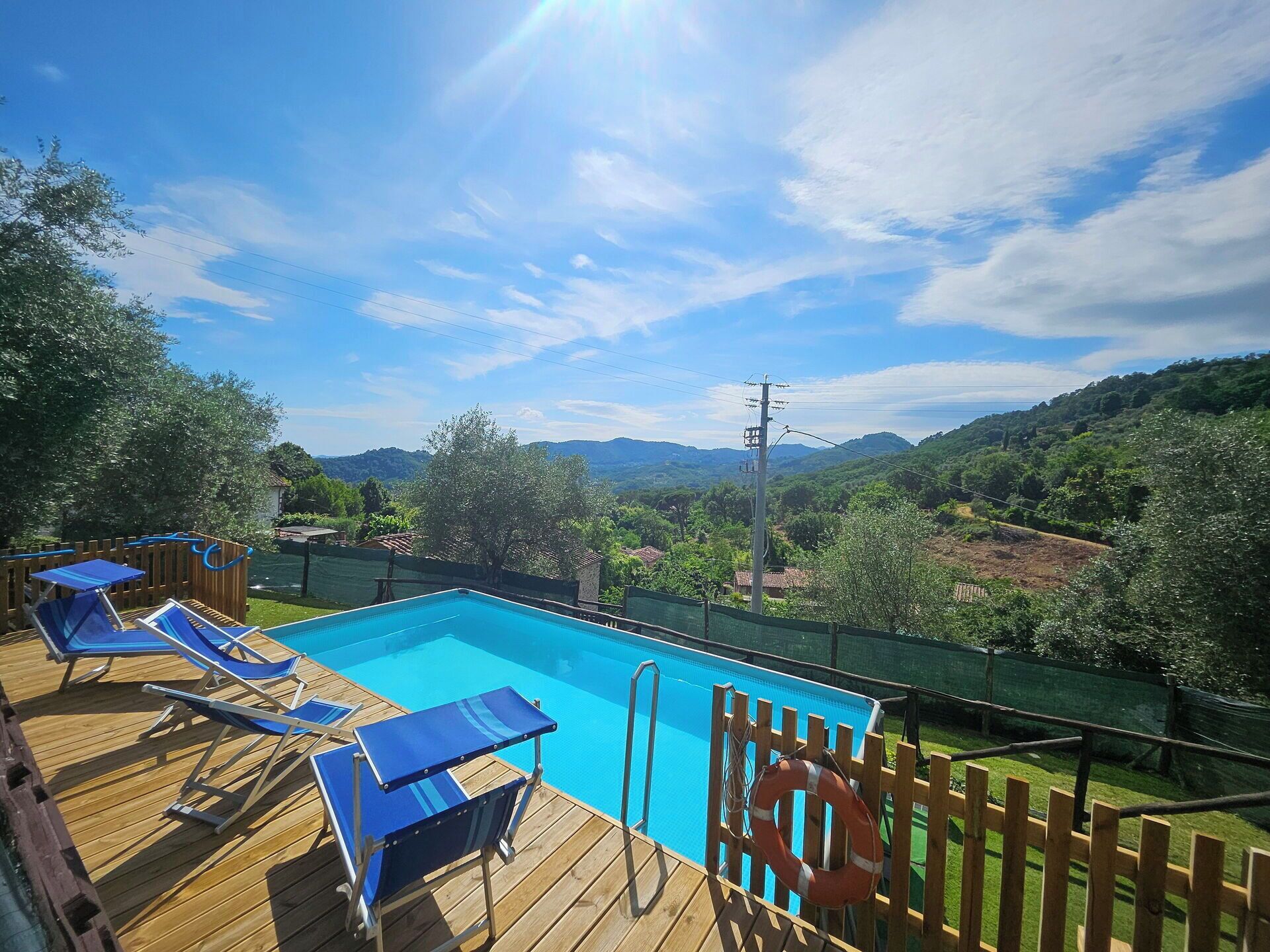 A swimming pool with blue lounge chairs and a wooden deck.