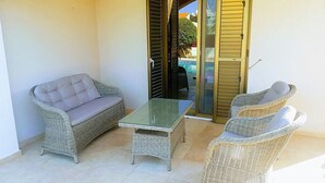 A patio area with wicker furniture, including a sofa and two chairs, and a glass-top table. - Stunning, Stylish and Spacious 3 Bedroom Villa with a Private Pool (Emba)