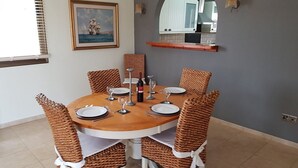 A dining area with a round table set for six, surrounded by wicker chairs with white cushions. - Stunning, Stylish and Spacious 3 Bedroom Villa with a Private Pool (Emba)