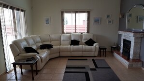 A living room with a beige sectional sofa, a fireplace, and a tiled floor. - Stunning, Stylish and Spacious 3 Bedroom Villa with a Private Pool (Emba)