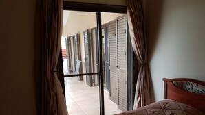 A bedroom with a bed, curtains, and a view of an outdoor area with a chair and a table. - Stunning, Stylish and Spacious 3 Bedroom Villa with a Private Pool (Emba)
