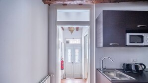 A narrow hallway leading to a door with a fire extinguisher on the wall.