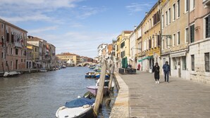 A canal with boats docked along the side, surrounded by historic buildings with balconies.