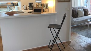 Una cocina moderna con una isla central, un área de comedor con sofá y vistas al exterior.