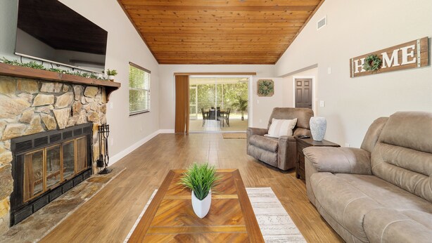 A living room with a stone fireplace, a flat-screen TV, a ceiling fan, and a 'HOME' sign on the wall. - 3/2 NEWLY REMODELED HOME IN CRYSTAL RIVER! Bring your boat and RV/Camper!  (Crystal River)