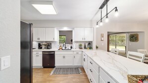 A modern kitchen with white cabinets, a black refrigerator, and a marble countertop. - 3/2 NEWLY REMODELED HOME IN CRYSTAL RIVER! Bring your boat and RV/Camper!  (Crystal River)