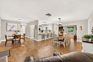 A spacious living area with a leather sofa, a dining table with chairs, and a kitchen in the background.