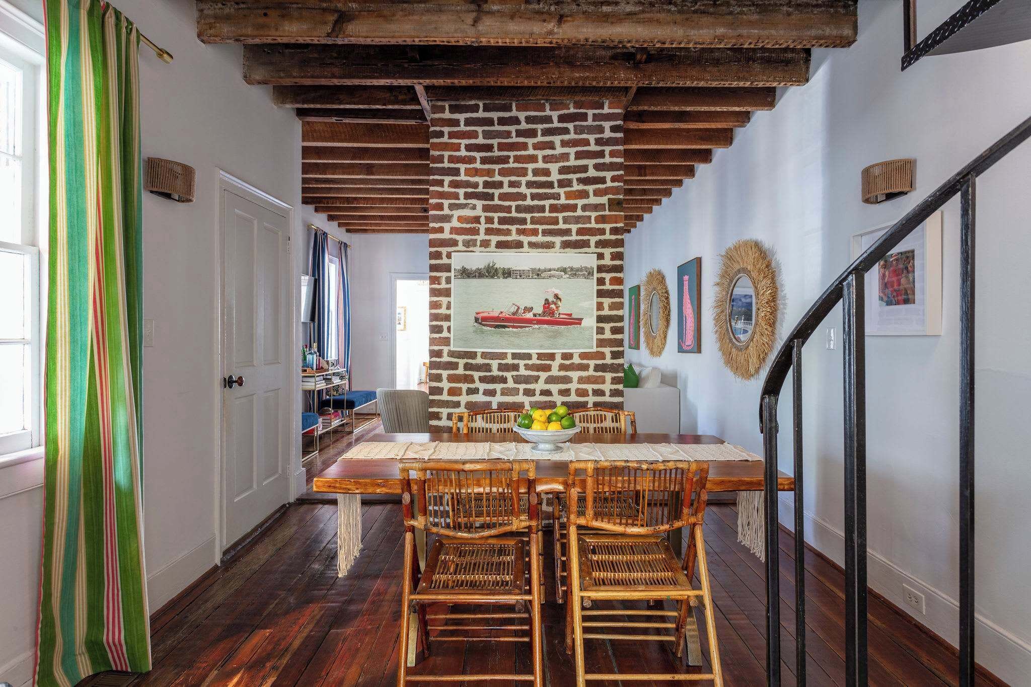 A dining area with a brick wall, wooden ceiling beams, and a table set for four.