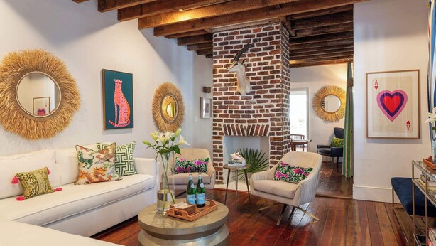 A cozy living room with a white sofa, a round coffee table, and a fireplace. - Casa Zoë | Cabana House – Bold Design, Prime Location (Charleston)